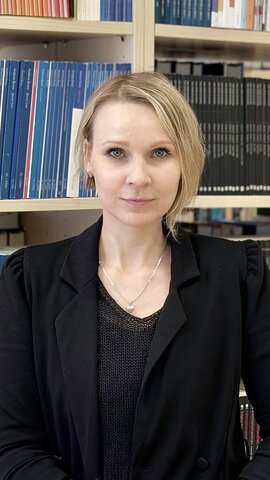 Naine mustas &uuml;likonnas raamatukogus raamaturiiulite ees